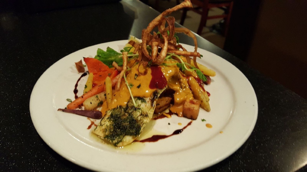A plated seafood entree with vegetables and sauce.