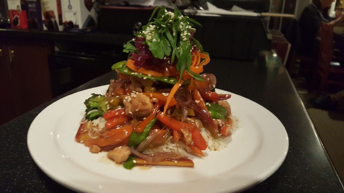 A stacked stir-fry and rice dish with vegetables.